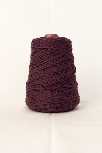 A cone of beetroot-colored acrylic tufting yarn.