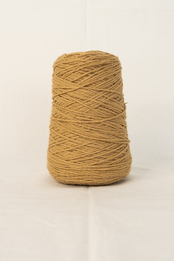 A large cone of camel colored tufting yarn made of acrylic, placed on a plain background.