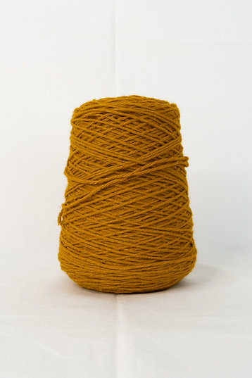 A cone of cinamon acrylic tufting yarn on a white background.