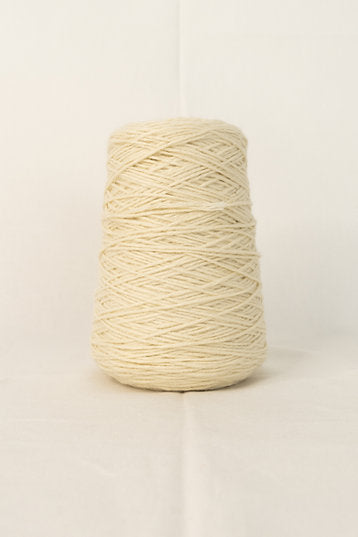 A cone of cream-colored tufting yarn placed against a neutral background.