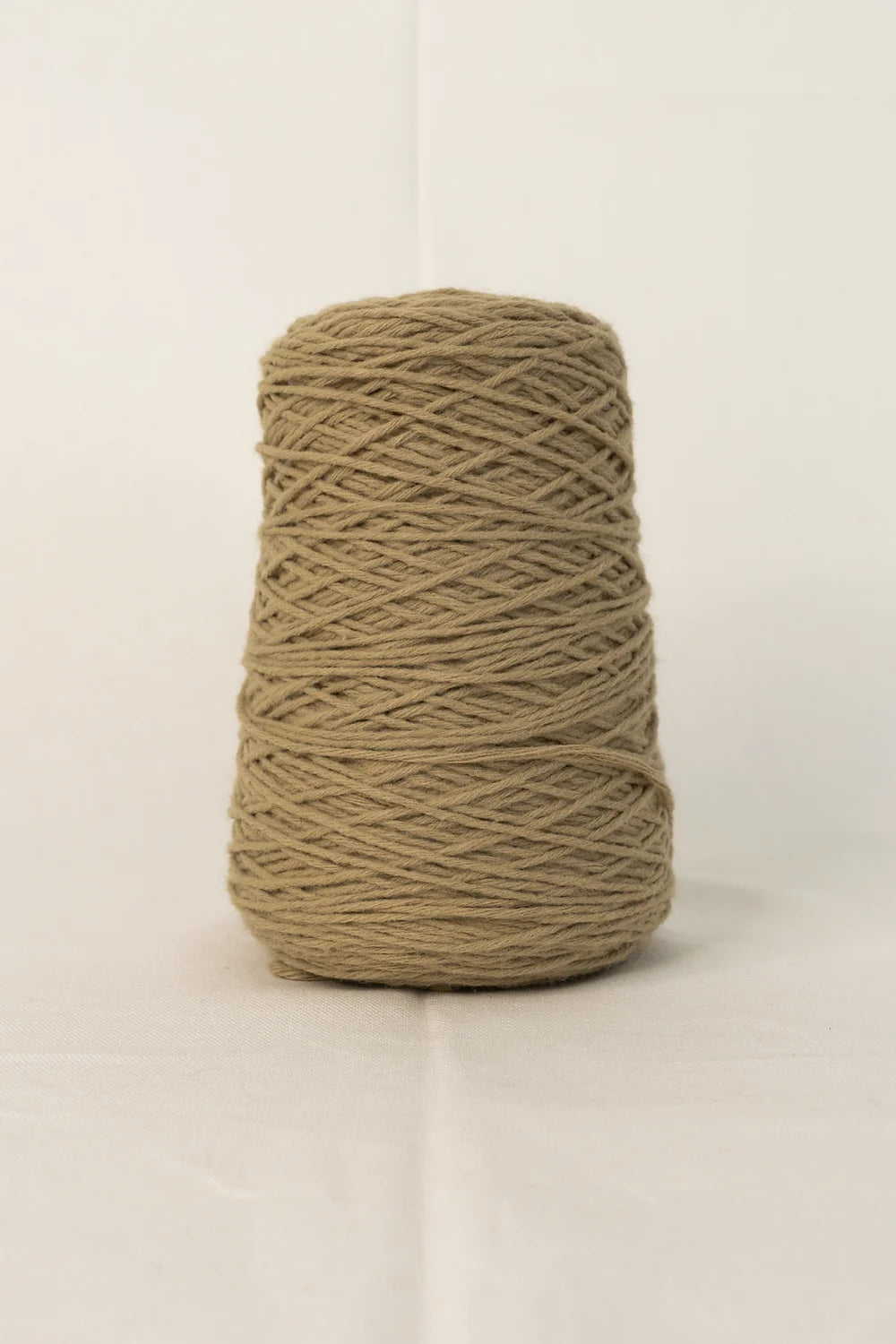 Cone of light brown tufting yarn on white background