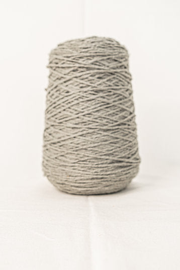A gray cone of acrylic yarn on a white background, typically used for tufting projects.
