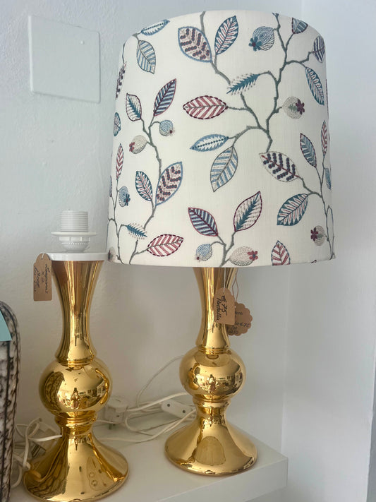 Two Gold table lamp with a floral-patterned lampshade on a white surface.