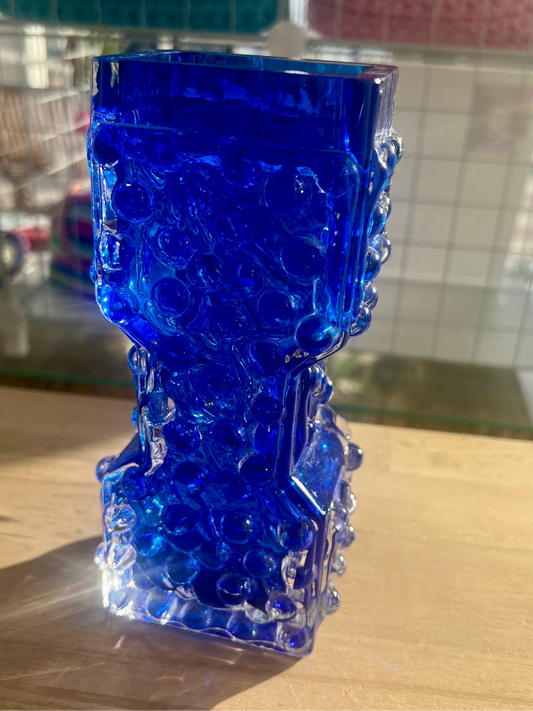 Blue glass vase on a wooden surface with a blurred background