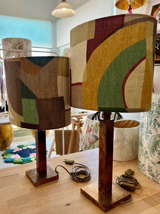 Two table lamps with retro-patterned linen shades on a wooden surface.