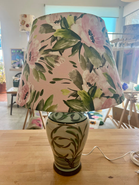 Ceramic lamp with pink floral-patterned shade on a wooden surface