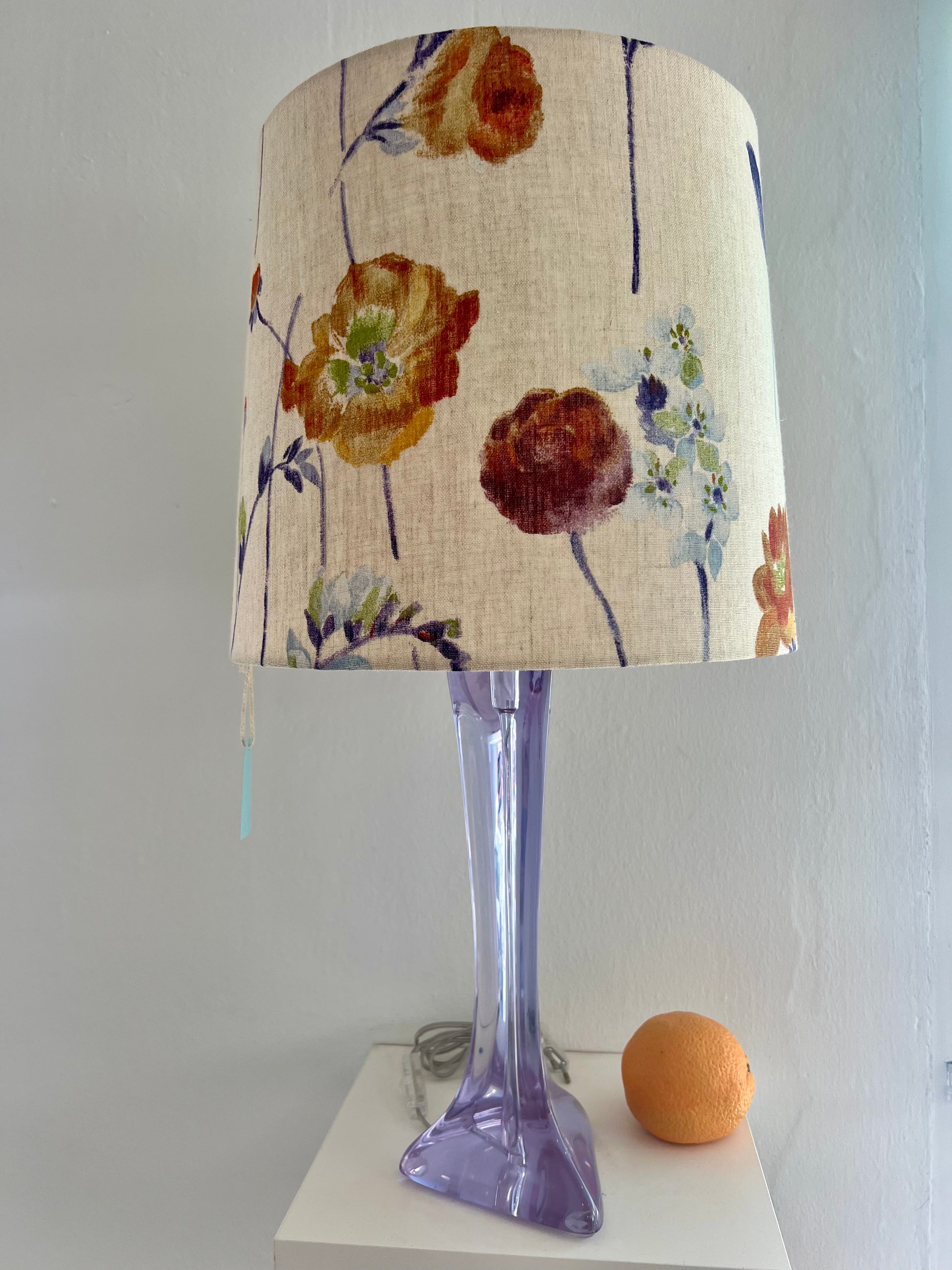Lavender glass lamp with a floral-patterned shade on a white surface