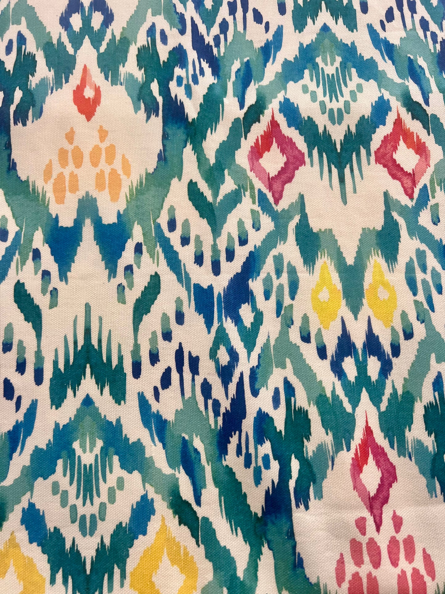 Multicolored ikat pattern on fabric in blue, green, teal with yellow, pink and orange accents