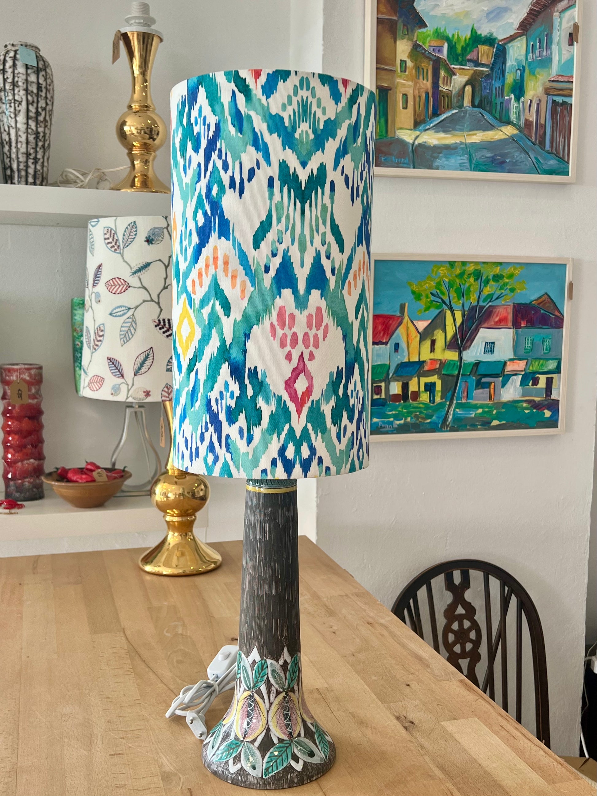 Decorative ceramic lamp with a colourful blue and teal lampshade on a wooden workbench