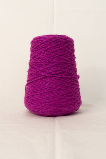 A cone of magenta tufting yarn placed against a white background.