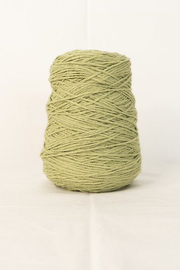 A cone of green acrylic tufting yarn.