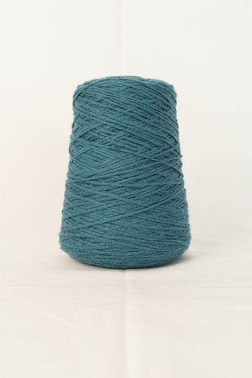 A cone of petrol blue acrylic yarn placed against a neutral background.