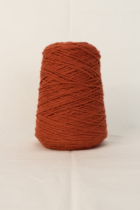 A cone of rust-colored acrylic tufting yarn.
