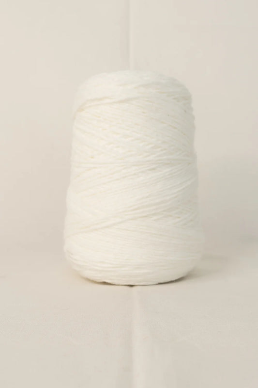 A large cone of white tufting yarn on a plain background.