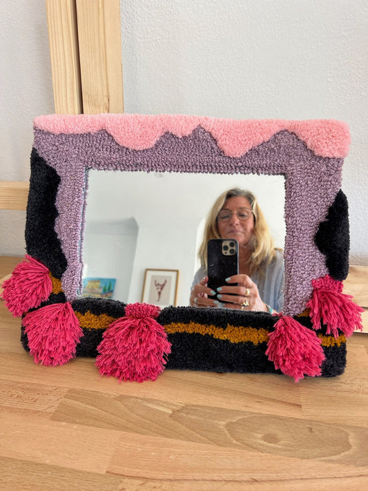 tufted framed mirror in pinks and purples, with reflected image of Katie Miles taking the picture