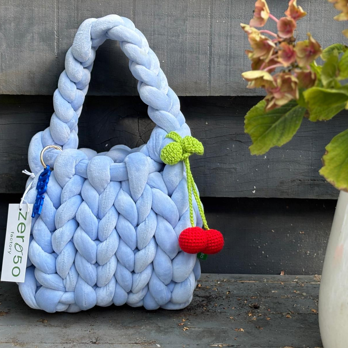 Blue braided bag with decorative elements on a wooden surface