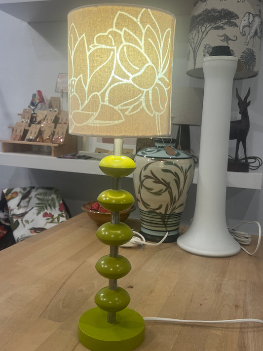 Green wooden lacquered sputnik table lamp with floral design on beige shade on a wooden surface