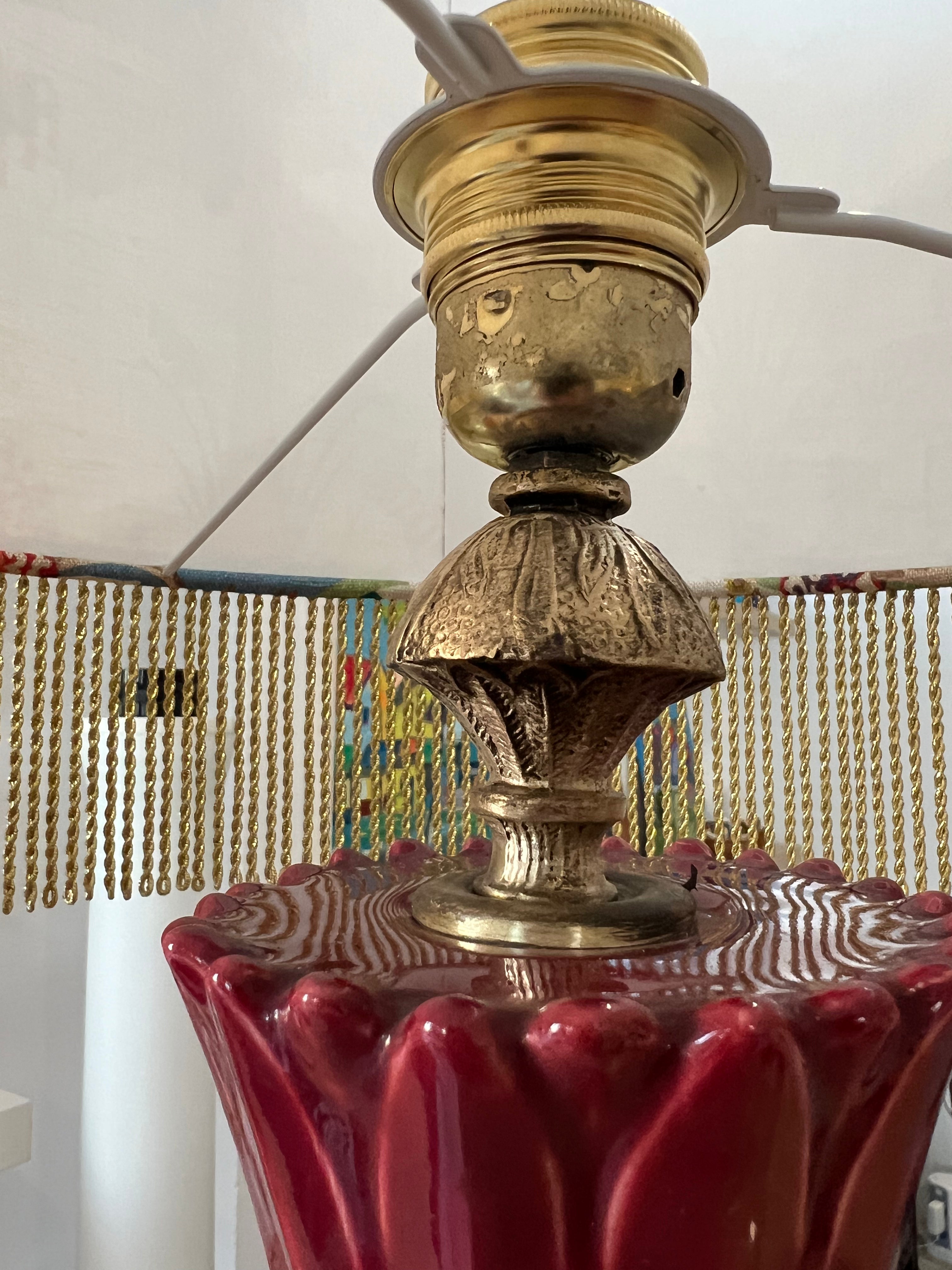 Close-up of a vintage lamp with brass fitting and red ceramic base Manises