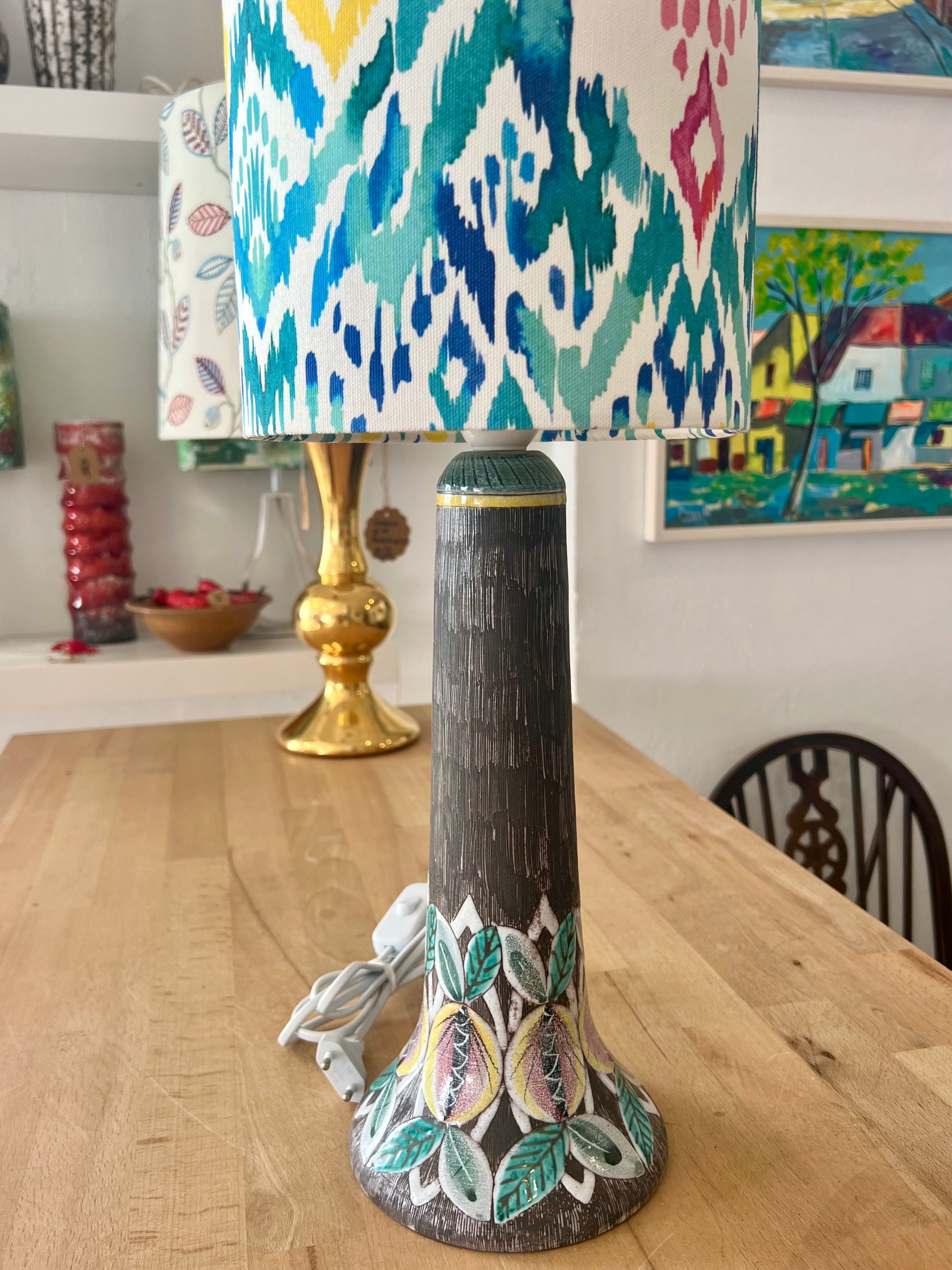 Decorative ceramic table lamp with an ikat-patterned lampshade on a wooden workbench